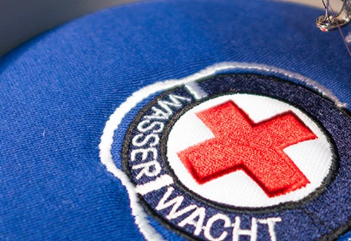 Gesticktes Wasserwachtlogo auf blauem Grund.